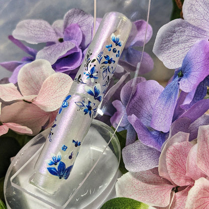 Decorative pen with floral design on a bed of pink and purple flowers