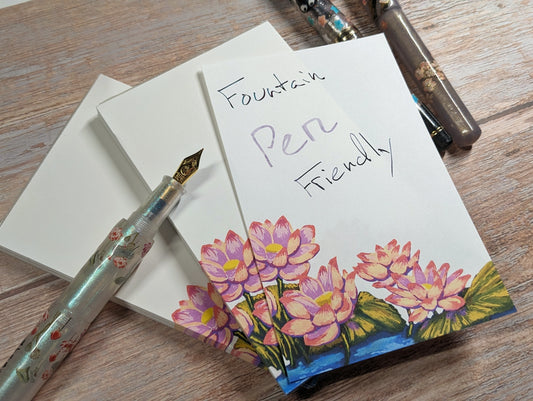 Notebook with floral design and fountain pen on a wooden surface