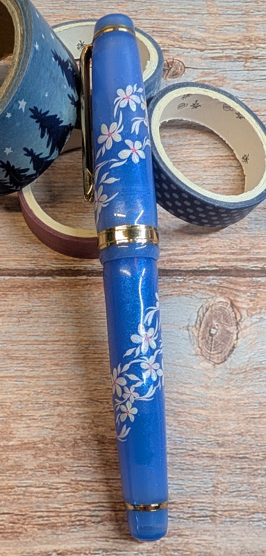 Purple fountain pen with floral design on a wooden surface