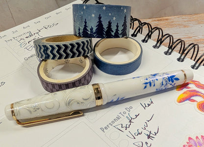Decorative white fountain pen pen with washi tape rolls on a planner page
